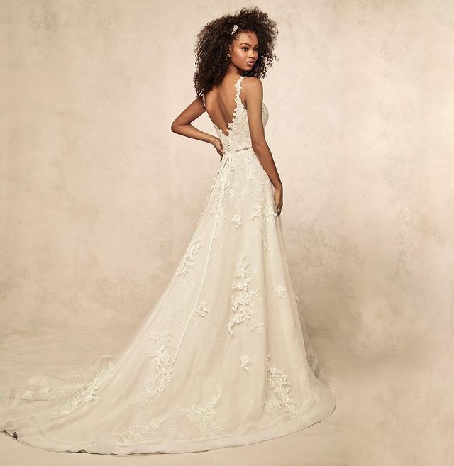 Mulher posando de costas com um vestido de noiva de alças com detalhes em renda por todo o vestido.